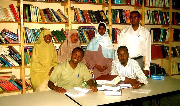 A group gathered around a desk in a library.